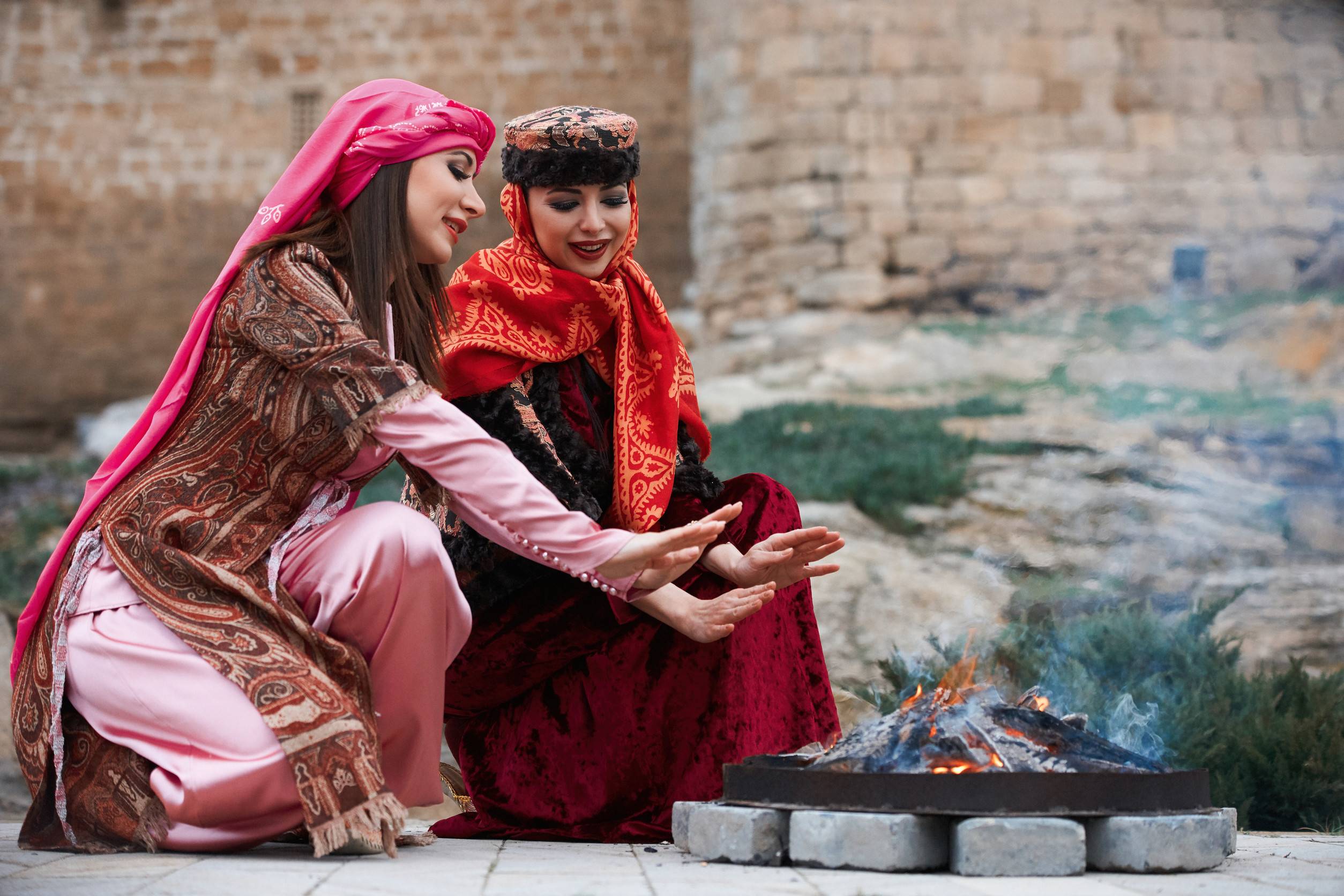 Bellissime donne azere in abiti tradizionali azerbaigiani che si scaldano le mani sopra il falò Bellissime donne azere in abiti tradizionali azerbaigiani che si scaldano le mani sopra il falò