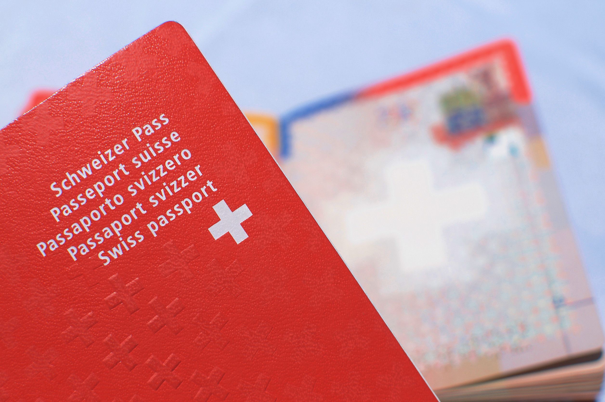 Primo piano di un passaporto svizzero con un passaporto svizzero aperto e sfocato sullo sfondo Primo piano di un passaporto svizzero con un passaporto svizzero aperto e sfocato sullo sfondo