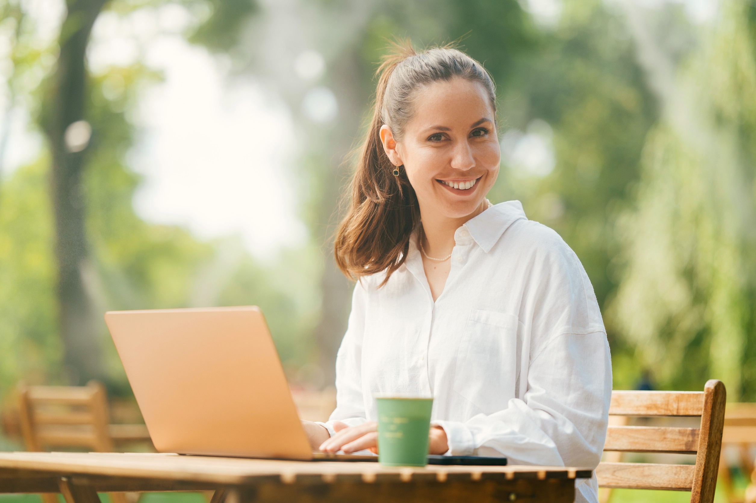 Una bella giovane donna si diverte a lavorare all'aperto, sulla terrazza di un bar in un parco Una bella giovane donna si diverte a lavorare all'aperto, sulla terrazza di un bar in un parco