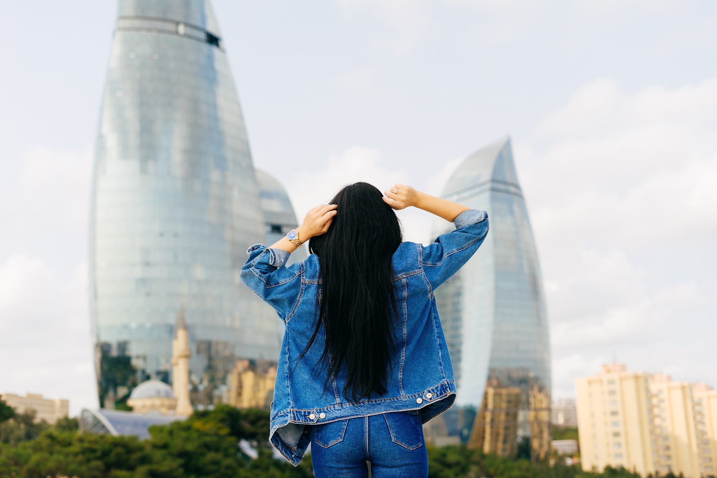 Ragazza bruna dai capelli lunghi viaggia in vacanza posando su uno sfondo di edifici moderni Ragazza bruna dai capelli lunghi viaggia in vacanza posando su uno sfondo di edifici moderni