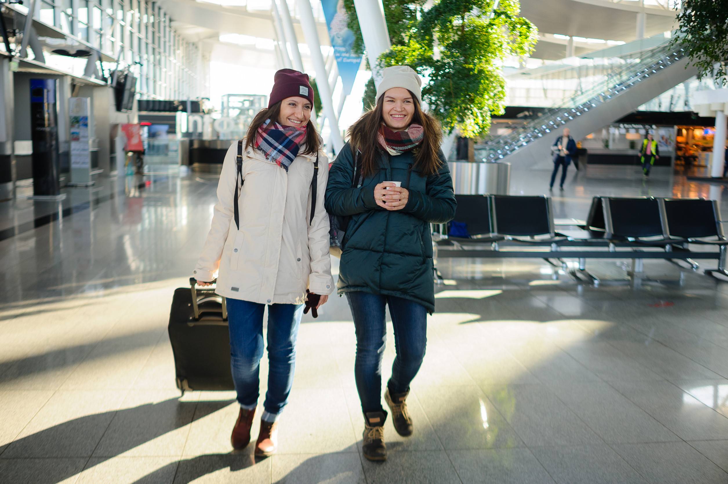 Passeggeri nella sala d'attesa dell'aeroporto Giovani donne aspettano il volo Una di loro tiene una valigia Passeggeri nella sala d'attesa dell'aeroporto Giovani donne aspettano il volo Una di loro tiene una valigia
