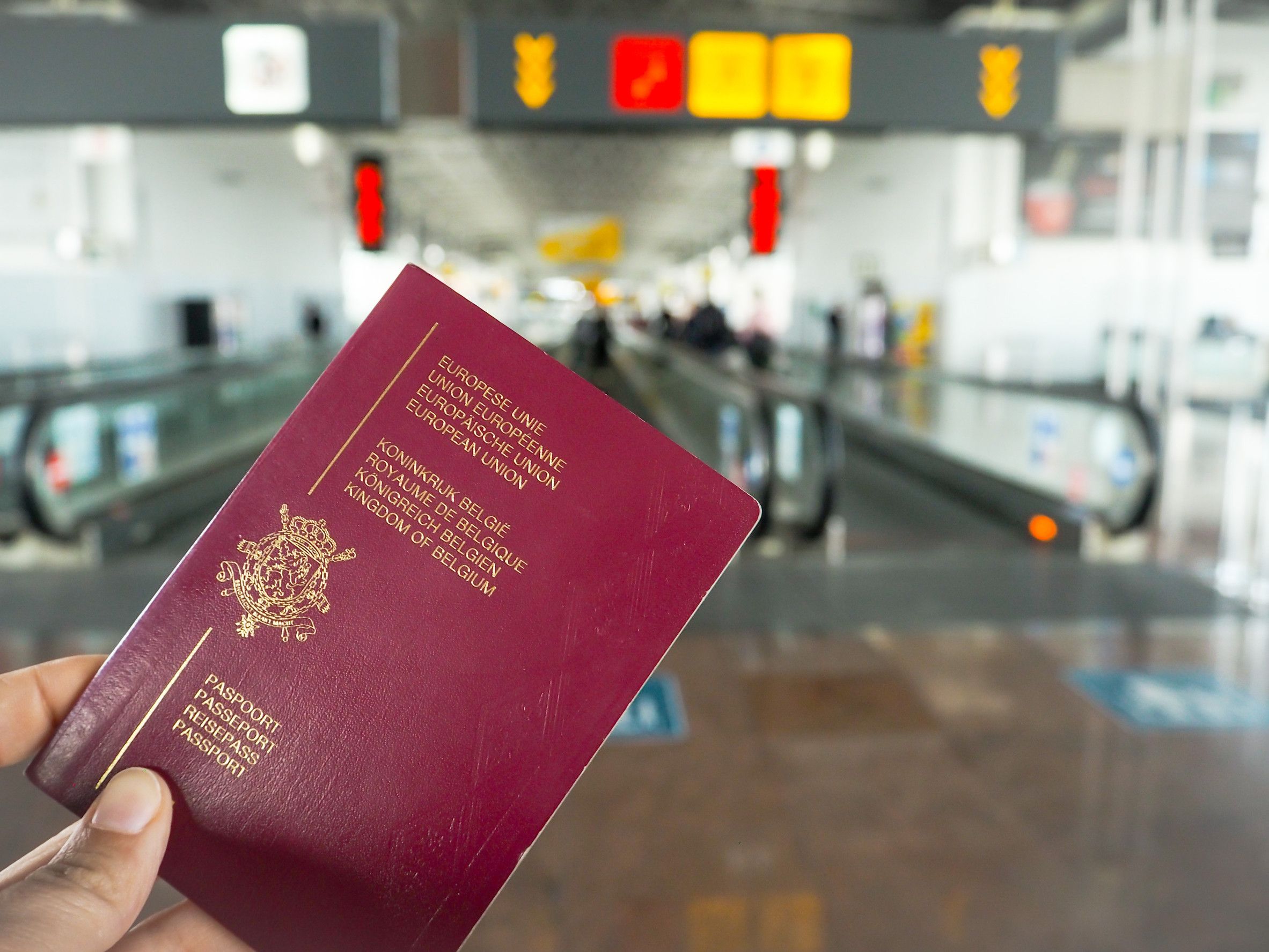 Persona in possesso di passaporto belga mentre cammina nel terminal di un aeroporto Persona in possesso di passaporto belga mentre cammina nel terminal di un aeroporto