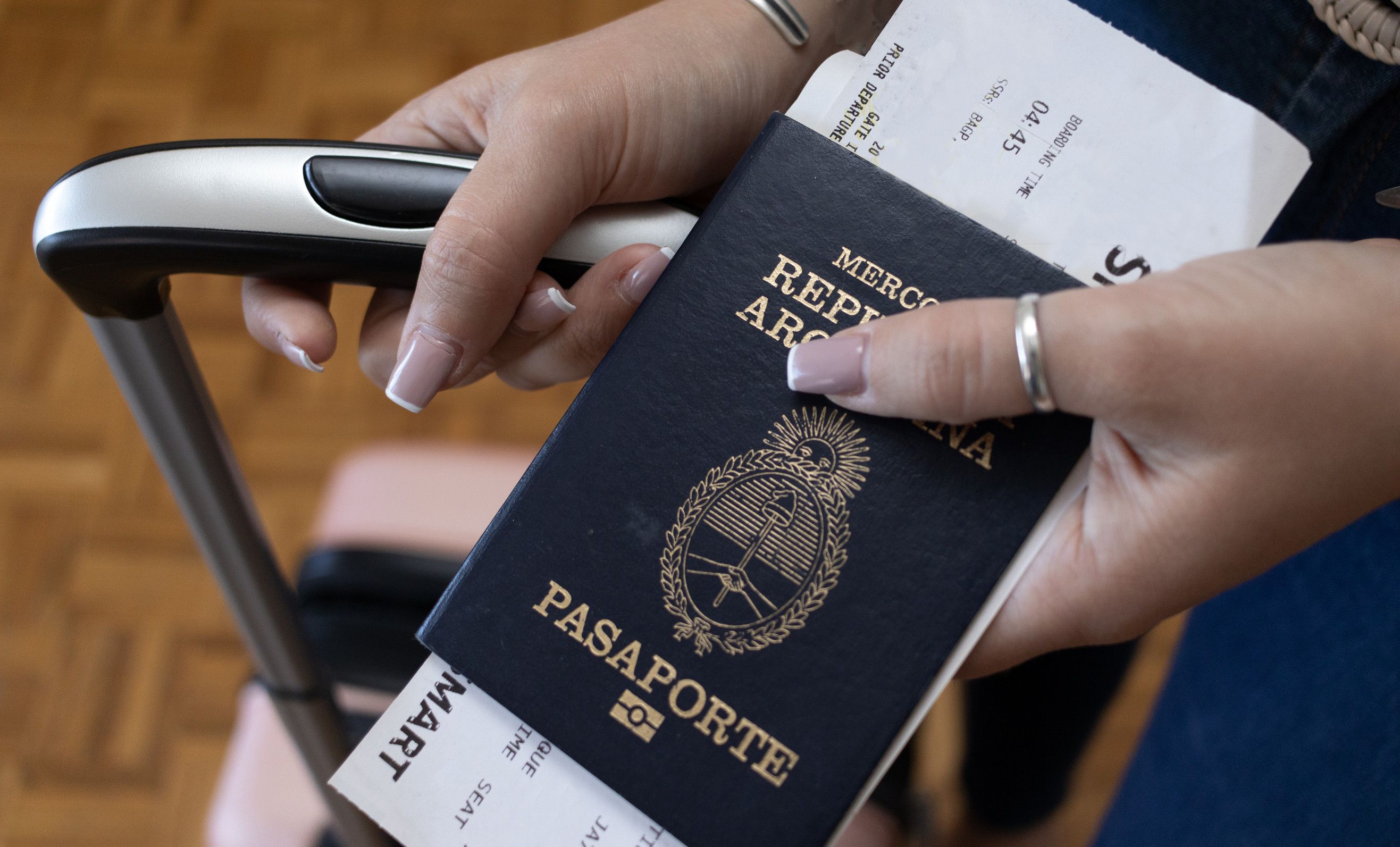 Ragazza che mostra il passaporto argentino con le sue borse da viaggio Traduzione del passaporto Ragazza che mostra il passaporto argentino con le sue borse da viaggio Traduzione del passaporto